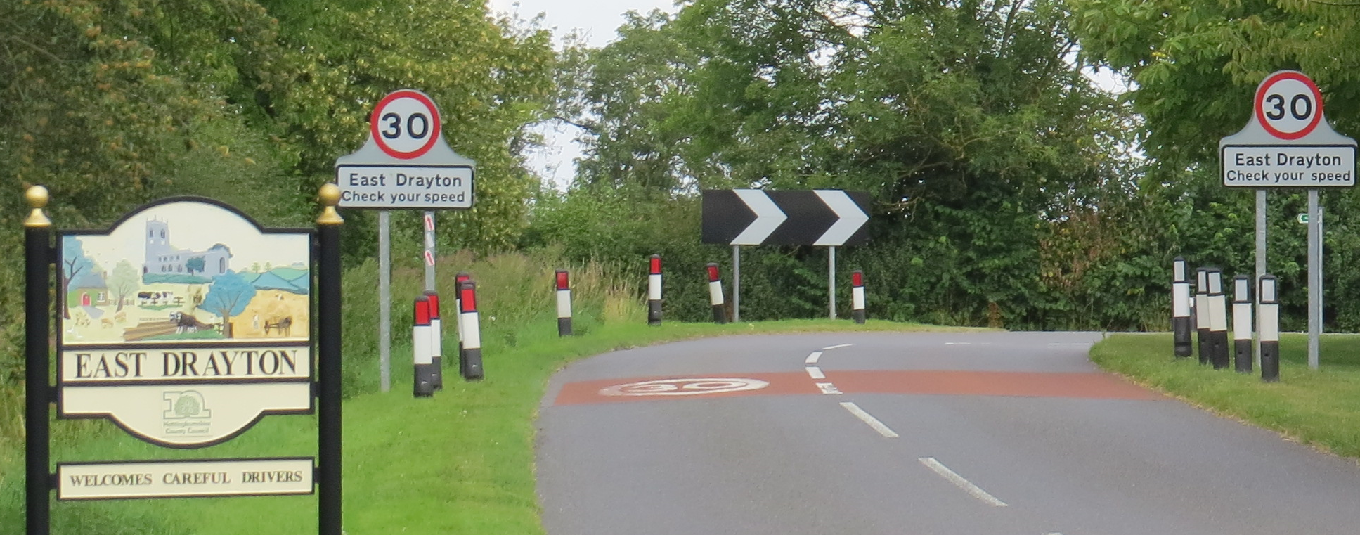 View of approach to village from South including village sign